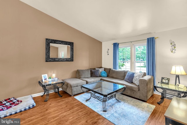 living area featuring vaulted ceiling, light wood-style floors, and baseboards