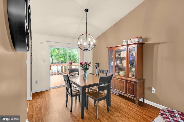 dining space featuring a chandelier, light wood-style floors, lofted ceiling, and baseboards