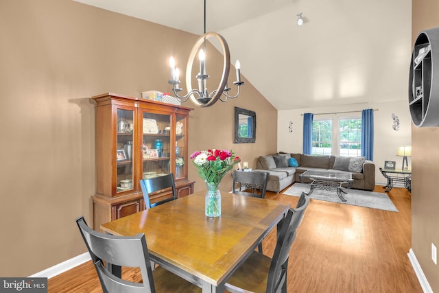 dining space with vaulted ceiling, wood finished floors, a chandelier, and baseboards