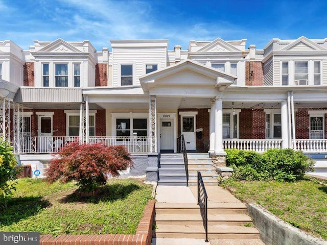 townhome / multi-family property with brick siding and covered porch