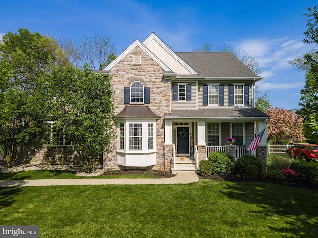 craftsman inspired home with stone siding, a porch, and a front lawn