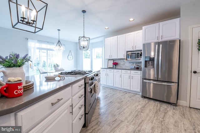 kitchen with stainless steel appliances, a chandelier, dark countertops, white cabinets, and recessed lighting