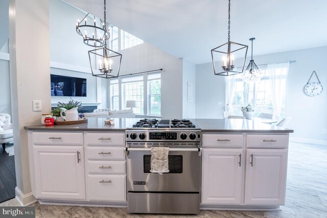 kitchen featuring a chandelier, gas stove, dark countertops, and white cabinetry