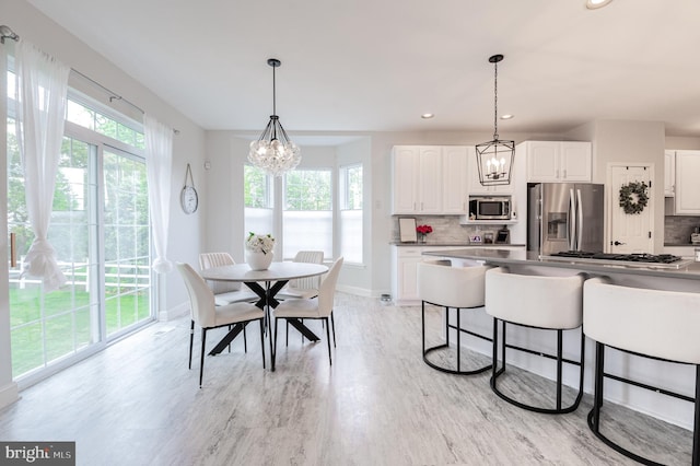 dining room featuring light wood-style floors, a chandelier, baseboards, and recessed lighting