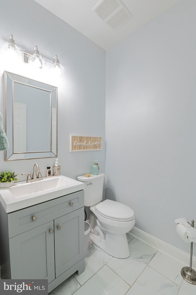 half bath featuring marble look tile flooring, toilet, vanity, and baseboards
