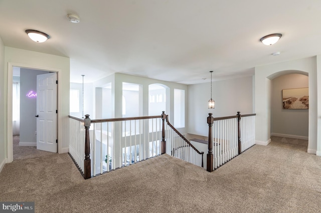 hallway with carpet floors, an upstairs landing, and baseboards