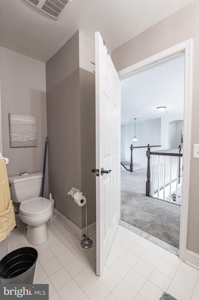 bathroom featuring toilet, baseboards, and tile patterned flooring