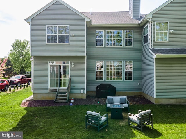 back of property with entry steps, a yard, a chimney, and an outdoor fire pit