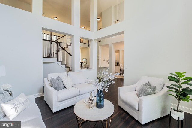 living area featuring dark wood-type flooring, stairs, and baseboards