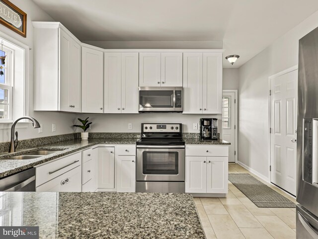 166 Spring Dale Ln, Felton, DE 19943 - kitchen featuring stainless steel appliances, a sink, white cabinetry, light tile patterned floors, and dark stone counters