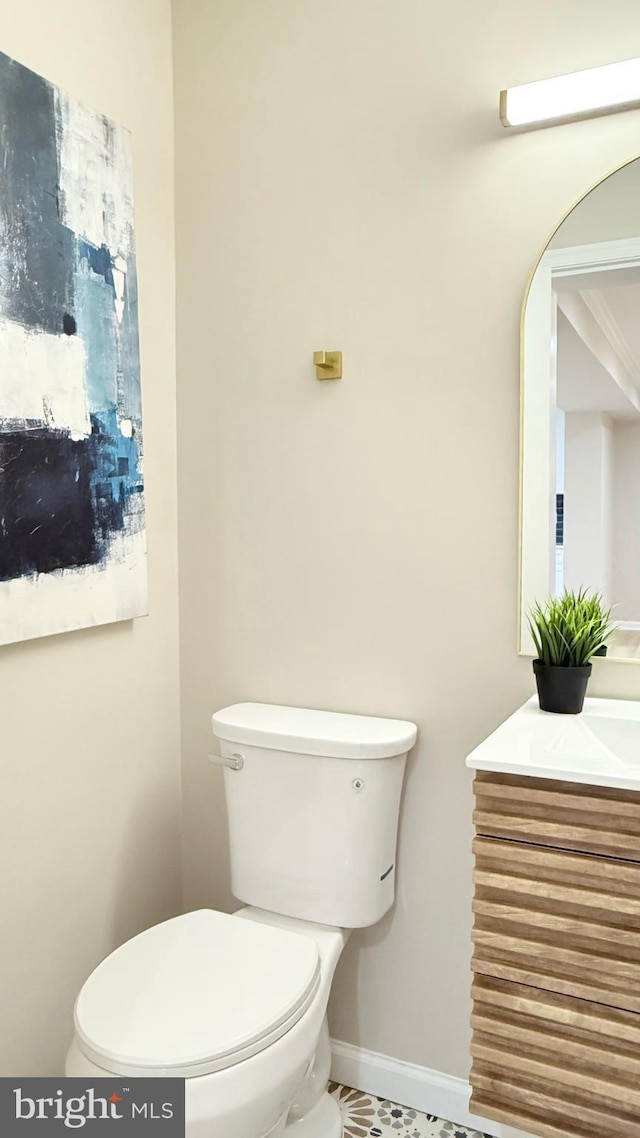 half bathroom with toilet, vanity, and baseboards