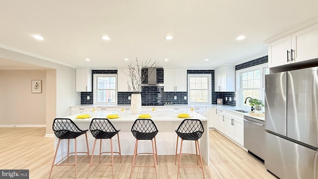 kitchen with stainless steel appliances, a kitchen bar, a sink, light wood-style floors, and recessed lighting