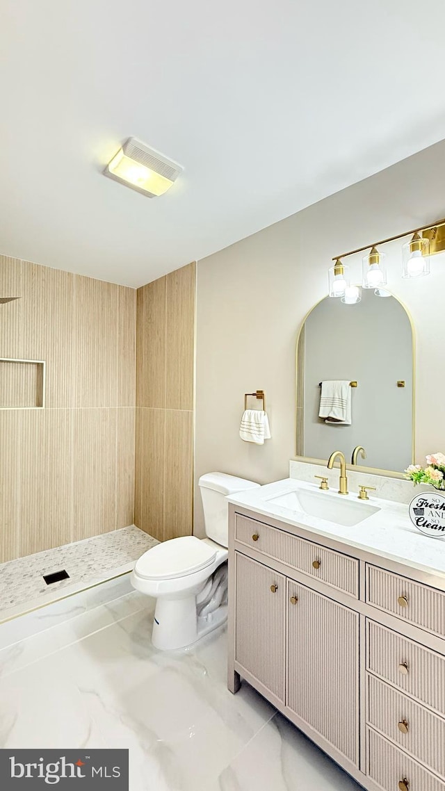 full bathroom with marble look tile flooring, vanity, toilet, and a tile shower