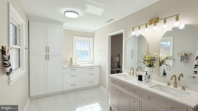 ensuite bathroom featuring double vanity, marble look tile flooring, and baseboards