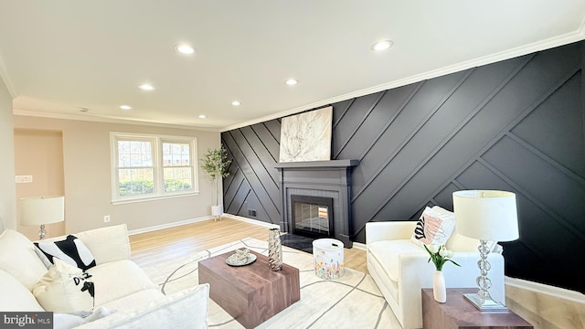 living area with recessed lighting, ornamental molding, light wood finished floors, a fireplace, and a decorative wall