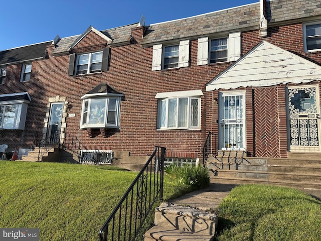 view of front of home with entry steps, a front lawn, and brick siding