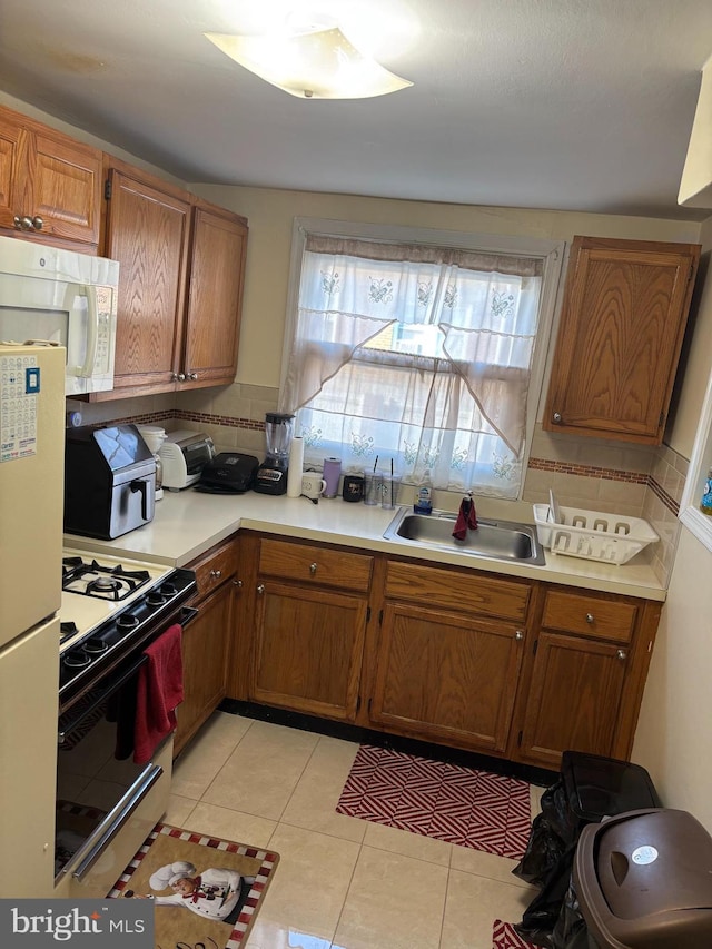 kitchen featuring a sink, white microwave, plenty of natural light, and range with gas cooktop