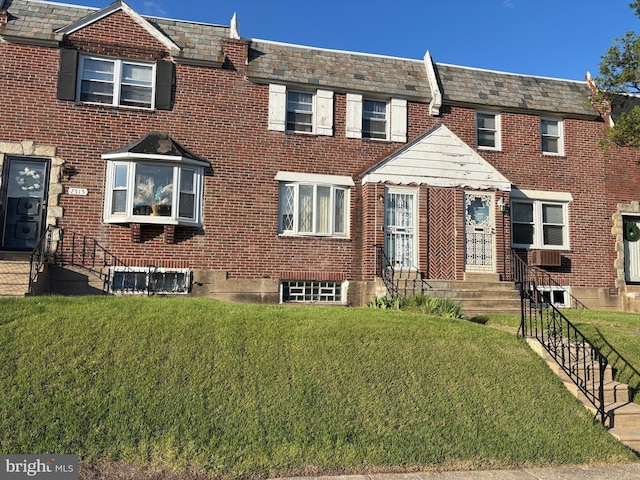 view of property with a front lawn, brick siding, and a high end roof