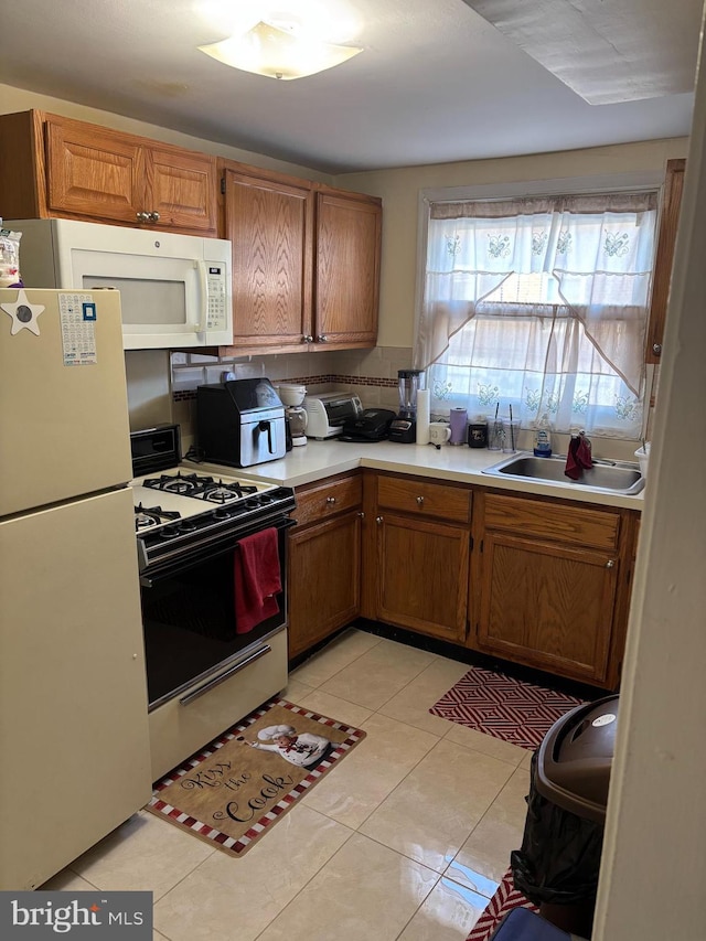 kitchen with white appliances, a sink, brown cabinetry, and light countertops