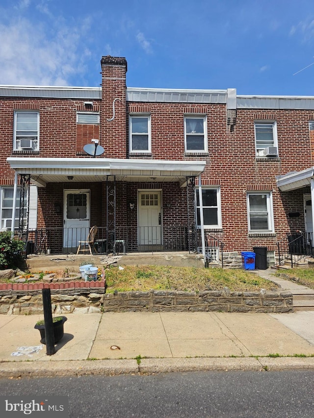 multi unit property with brick siding, cooling unit, and a porch
