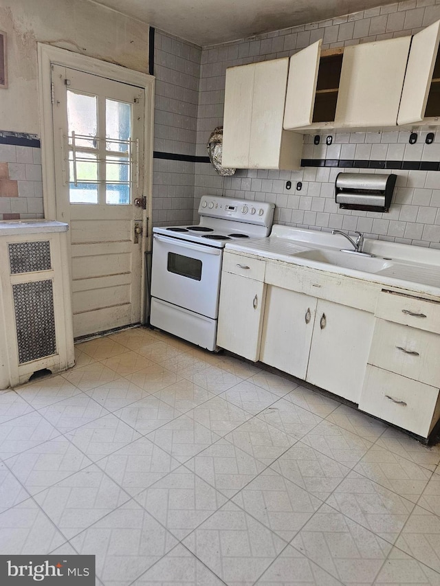 kitchen featuring white electric stove, open shelves, light countertops, a sink, and tile walls