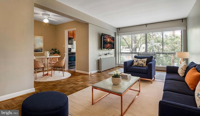 living room with radiator heating unit, baseboards, and a ceiling fan