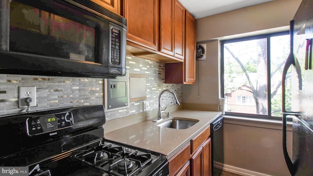 kitchen featuring black appliances, a sink, brown cabinetry, and healthy amount of natural light