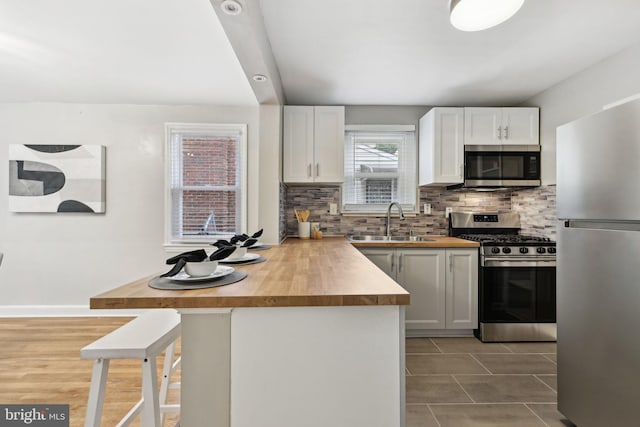 4850 Eastern Ave NE, Washington, DC 20017 - kitchen featuring stainless steel appliances, a sink, wooden counters, tasteful backsplash, and a peninsula
