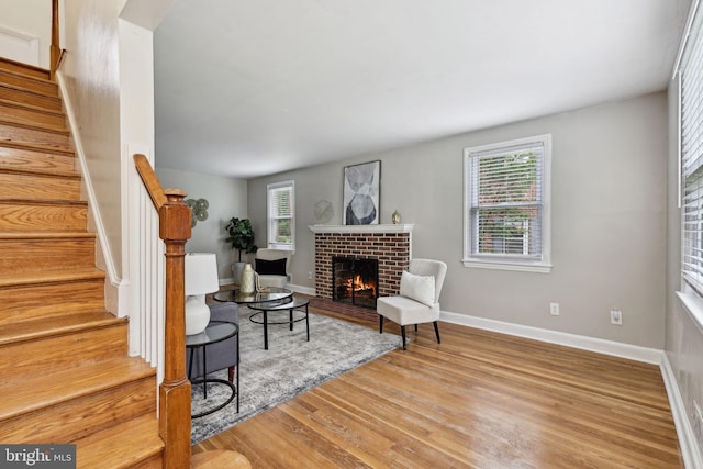 4850 Eastern Ave NE, Washington, DC 20017 - living room featuring wood finished floors, a brick fireplace, stairway, and baseboards