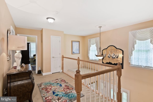 hallway with carpet flooring, an upstairs landing, and baseboards