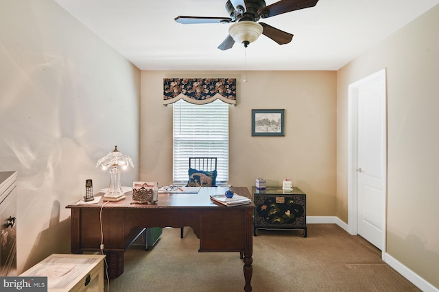 carpeted office space featuring a ceiling fan and baseboards