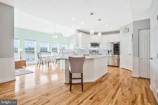 455 Creeks End Ln, Stevensville, MD 21666 - kitchen with stainless steel appliances, a peninsula, light wood-type flooring, white cabinetry, and backsplash