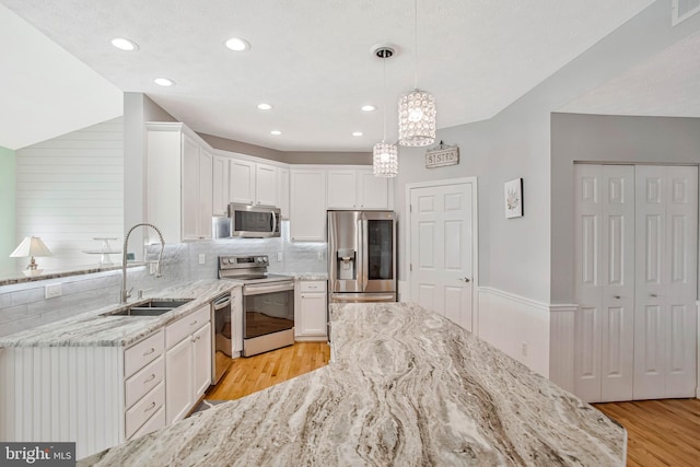 455 Creeks End Ln, Stevensville, MD 21666 - kitchen featuring stainless steel appliances, light wood-type flooring, a sink, white cabinets, and light stone counters