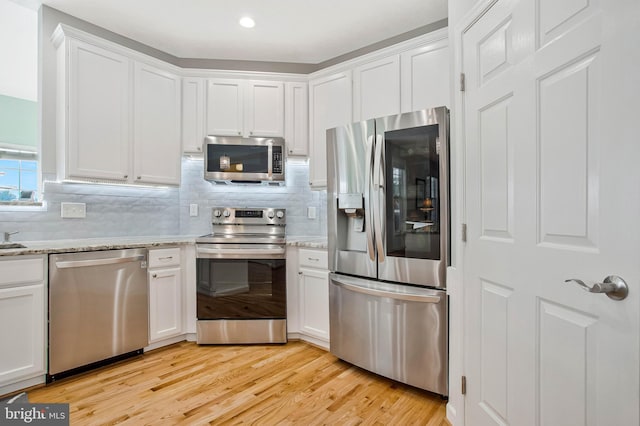 455 Creeks End Ln, Stevensville, MD 21666 - kitchen with stainless steel appliances, white cabinets, light wood-type flooring, tasteful backsplash, and light stone counters