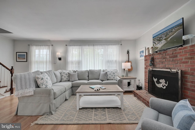 living area featuring wood finished floors, stairway, and a fireplace