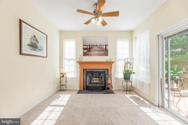 carpeted living room with baseboards, a fireplace with flush hearth, and ceiling fan