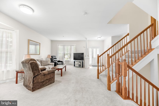 carpeted living area featuring stairs