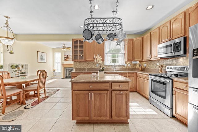 kitchen with appliances with stainless steel finishes, a kitchen island, decorative backsplash, light tile patterned floors, and recessed lighting