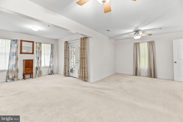 unfurnished living room featuring ceiling fan, healthy amount of natural light, and carpet