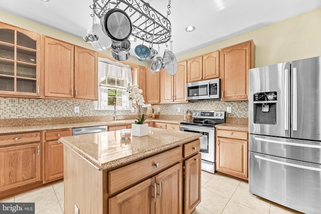 kitchen featuring appliances with stainless steel finishes, light tile patterned floors, glass insert cabinets, and light brown cabinetry