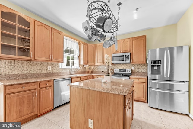 kitchen featuring stainless steel appliances, light tile patterned floors, a kitchen island, a sink, and backsplash
