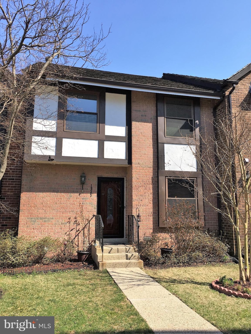 doorway to property featuring brick siding and a lawn