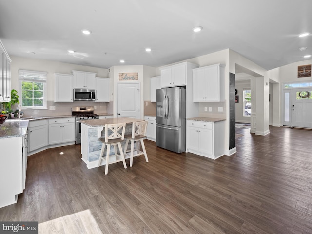 1422 Silver Oak Ln, Arnold, MD 21012 - kitchen featuring appliances with stainless steel finishes, a center island, a breakfast bar area, dark wood finished floors, and white cabinetry