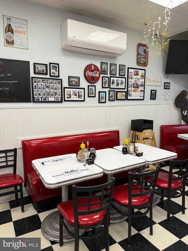 138 W 4th St, Bridgeport, PA 19405 - dining space with tile patterned floors, a wall mounted air conditioner, a wainscoted wall, and a paneled ceiling