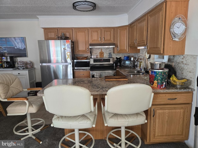 8 35th St Unit 401, Ocean City, MD 21842 - kitchen with appliances with stainless steel finishes, a sink, under cabinet range hood, brown cabinetry, and decorative backsplash