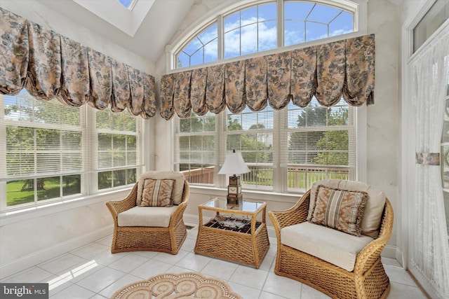 sunroom with a skylight, vaulted ceiling, tile patterned floors, and baseboards