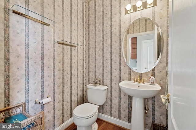 bathroom with toilet, wood finished floors, and baseboards
