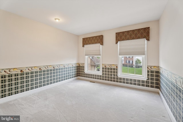 unfurnished room featuring wainscoting and carpet floors