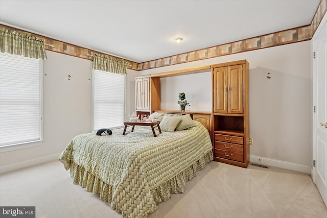 bedroom with light colored carpet and baseboards