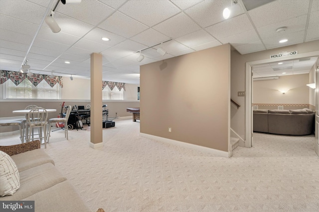 living area with a paneled ceiling, carpet, rail lighting, stairs, and baseboards